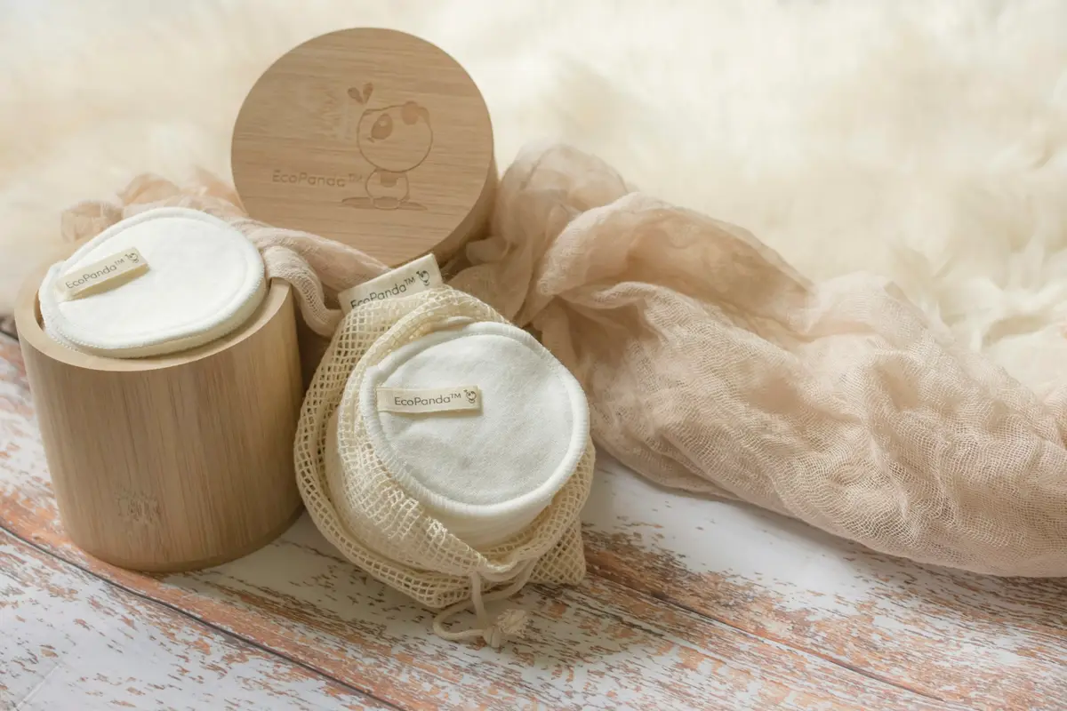 Disques démaquillants lavables en coton posés près d'un pot en bambou