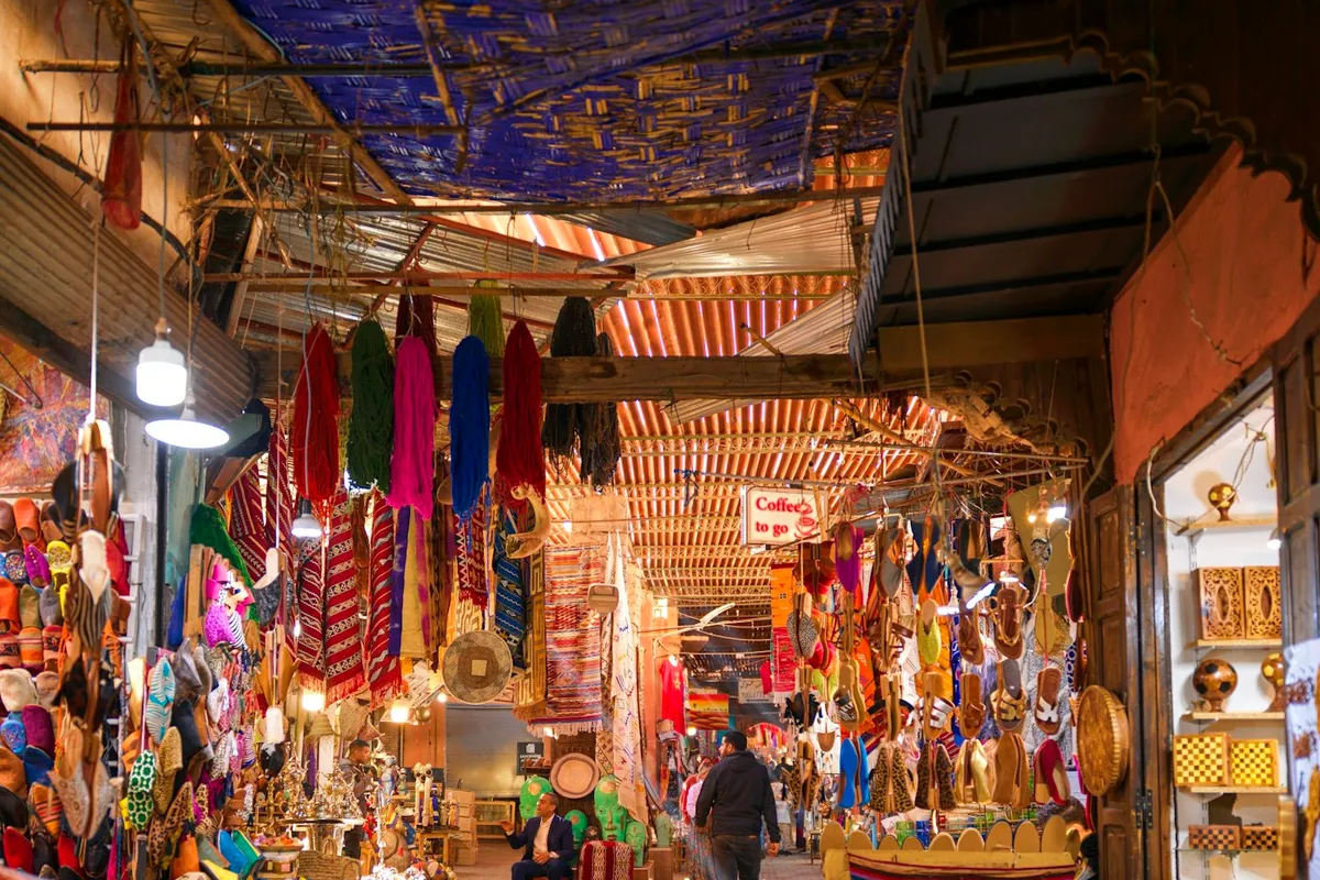 Allée couverte d'un souk à Marrakech, étals de tissus et de couleurs vives
