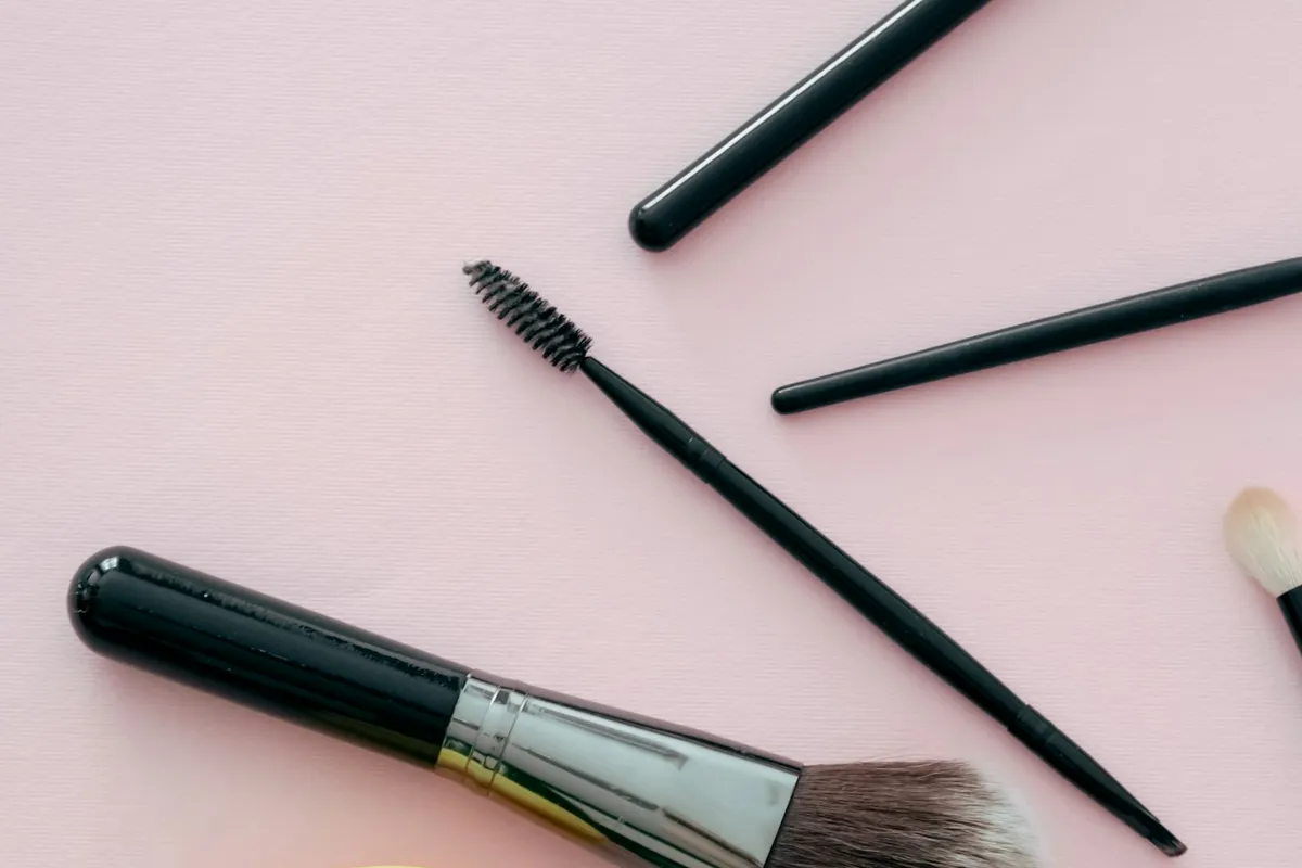 Pinceaux de maquillage de tailles différentes posés sur un fond rose pâle