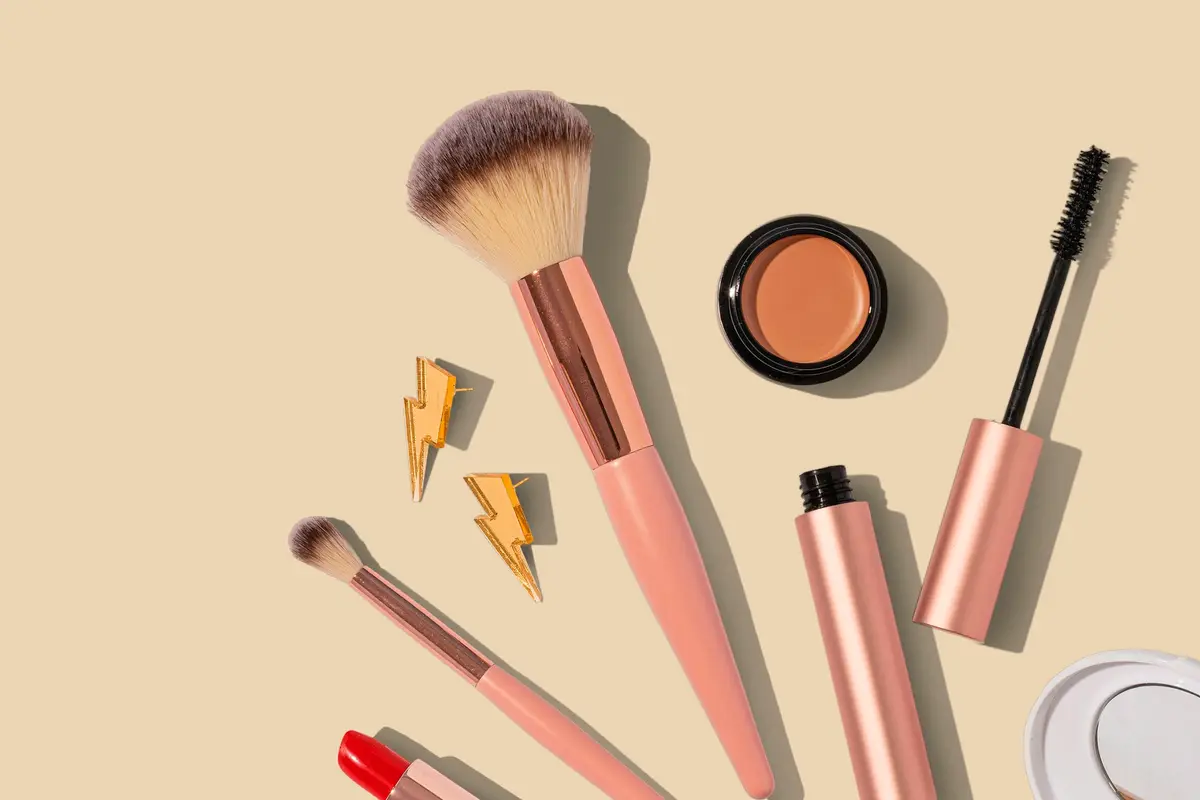 Pinceaux, blush, rouge à lèvres et mascara disposés à plat